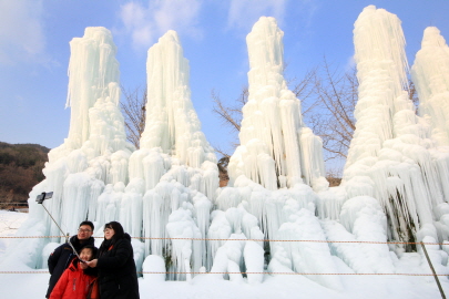 대형 얼음분수 앞에서 셀카봉으로 기념촬영 중인 가족
